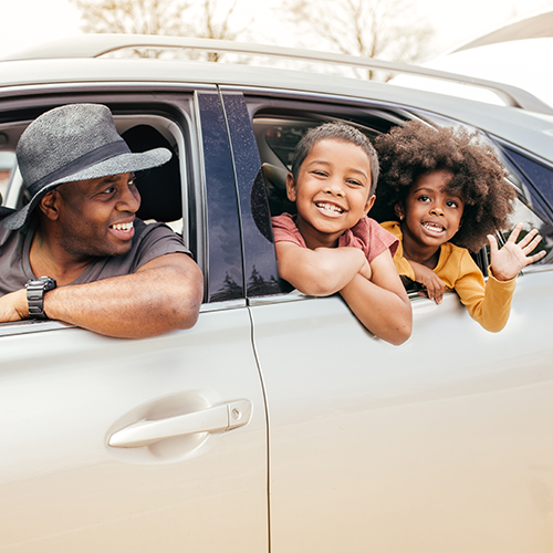 Father and kids smiling out of car windows.