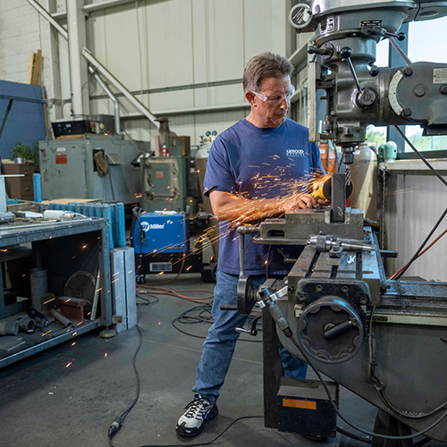 Man using grinding machine in workshop.