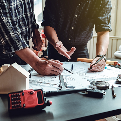 Close-up of two men's hands working on draft plans