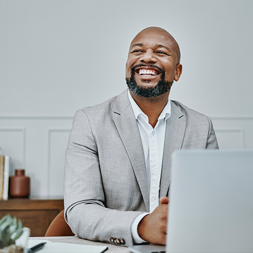 Smiling man wearing professional gray suit at desk.